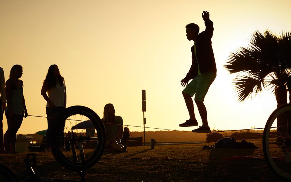 Silhouetted children playing on beach with sun in background